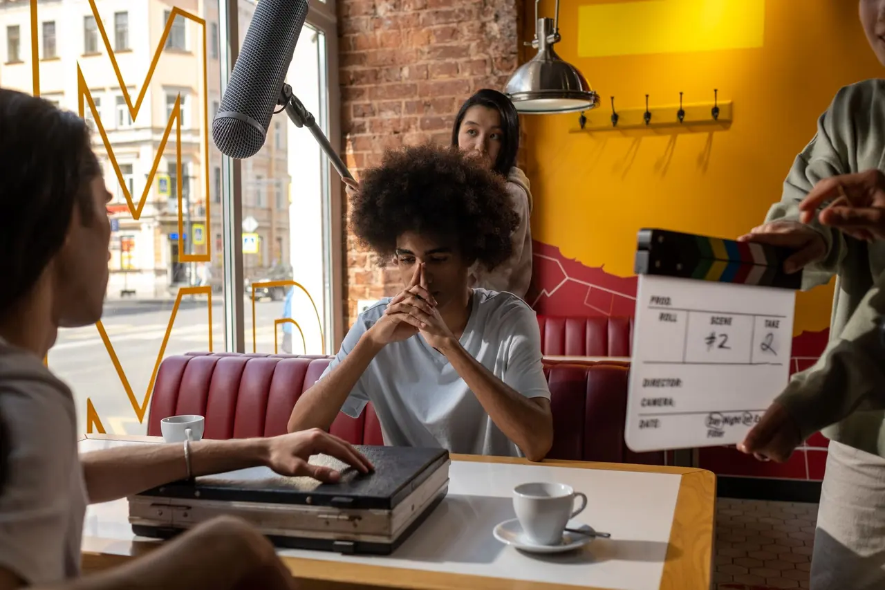 A film crew with a boom microphone and a clapperboard shooting a scene in a diner