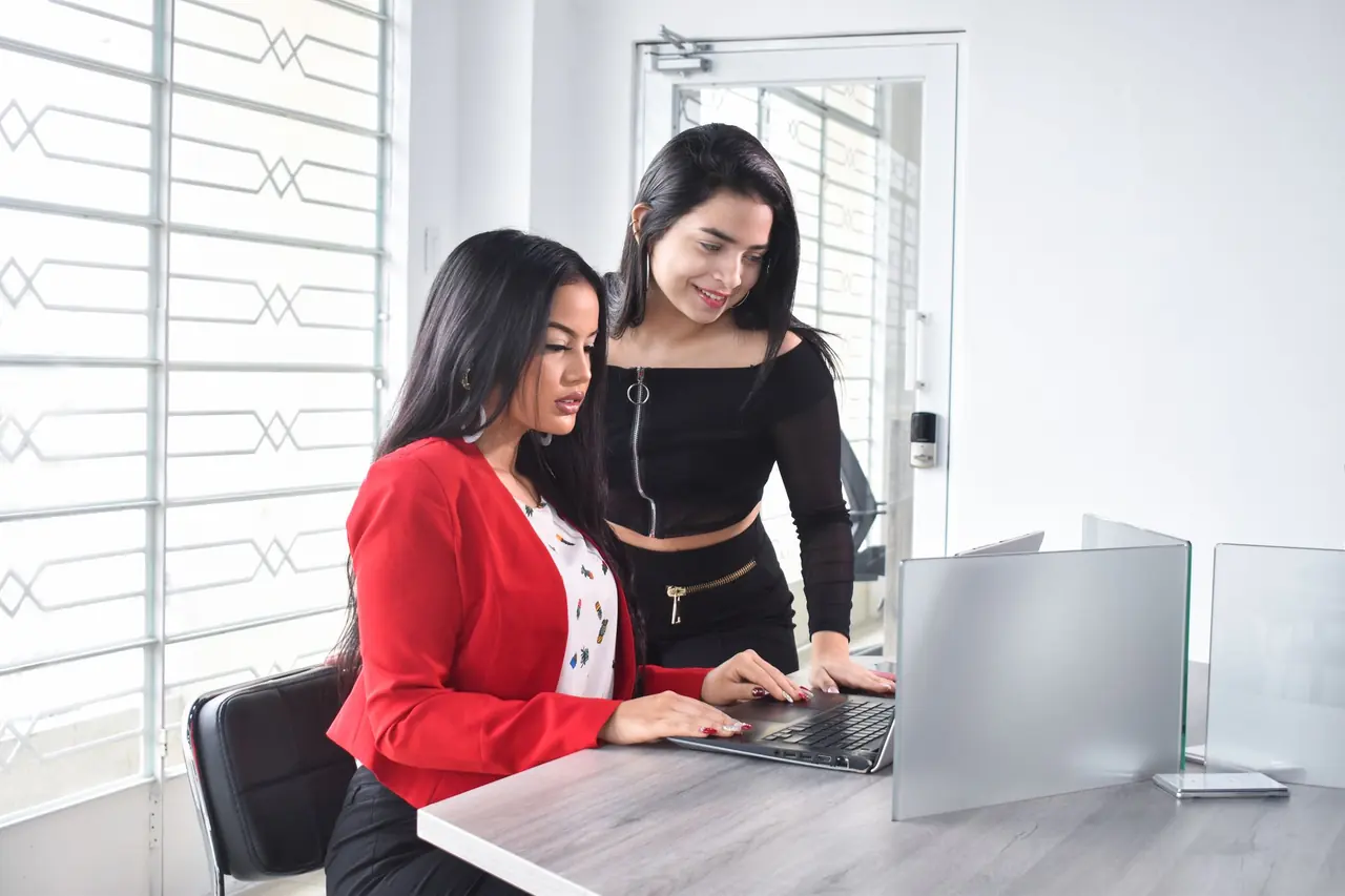 Two colleagues working together at a laptop in a bright office