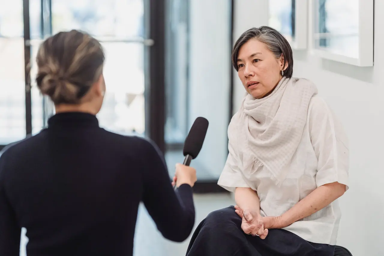 A journalist interviewing a woman with a handheld microphone