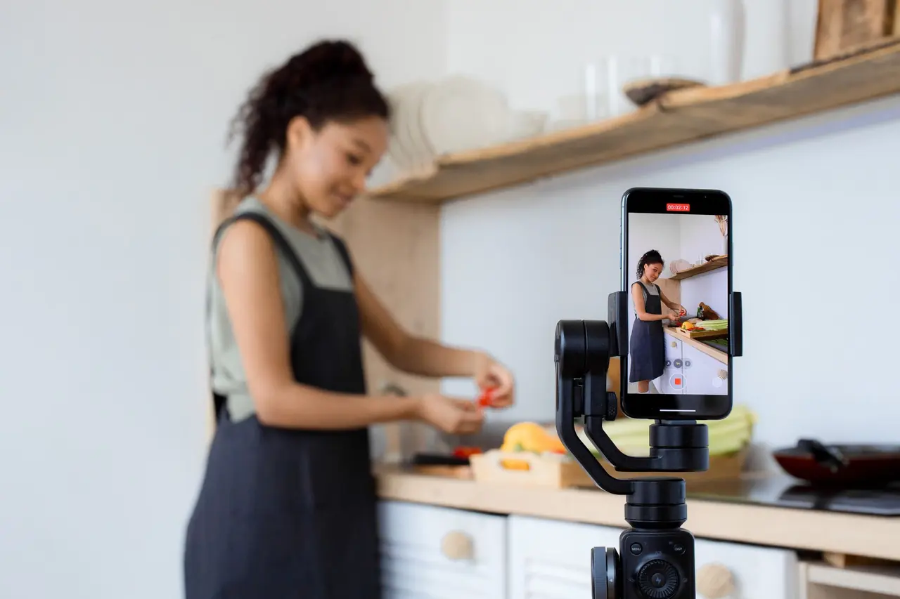 A woman filming a cooking video with her phone on a stand